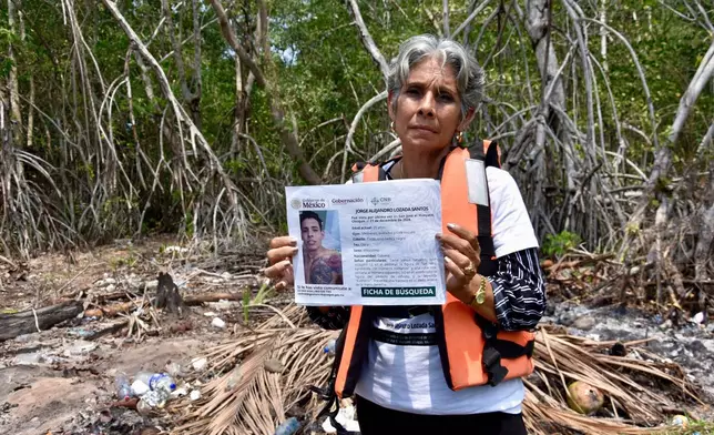 Alicia Santos Torres, from Cuba, shows a sign of her missing son Jorge Alejandro Lozada in San Jose Hueyate, Chiapas state, Mexico, Saturday, May 9, 2026, during a search for migrants who vanished in late 2024 along a maritime smuggling route to the U.S. (AP Photo/Edgar H. Clemente)