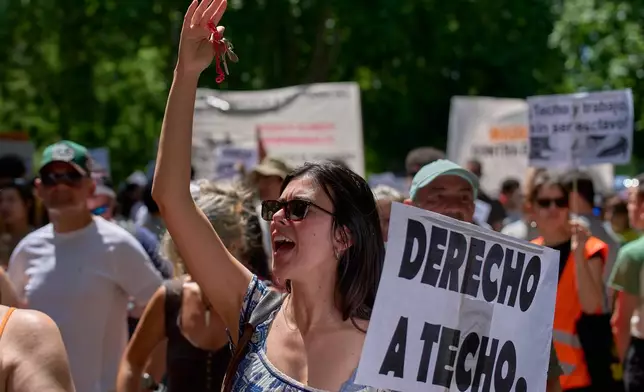 A woman holds a banner reading in Spanish: "Right to housing" during a protest in Madrid, Spain, Sunday, May 24, 2026, against rising housing costs that are pricing many Spaniards out of the market amid Spain's broader housing crisis. (AP Photo/Manu Fernandez)
