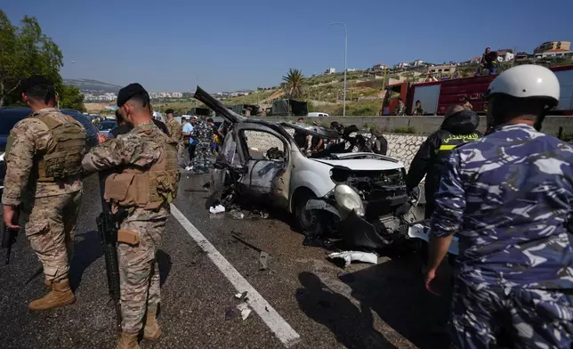 Security forces and emergency responders gather around a damaged vehicle at the scene of an Israeli airstrike that hit a car in the coastal town of Saadiyat, south of Beirut, Lebanon, Saturday, May 9, 2026. (AP Photo/Hassan Ammar)