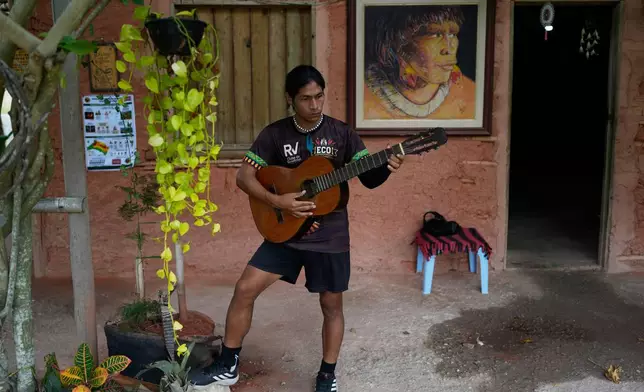 Edilson Nunes da Silva, a player of Originarios, a new soccer team in Rio's fifth division made up exclusively of Indigenous players, plays the guitar at his home in Mata Verde Bonita village in Marica, Brazil, Tuesday, April 28, 2026. (AP Photo/Silvia Izquierdo)