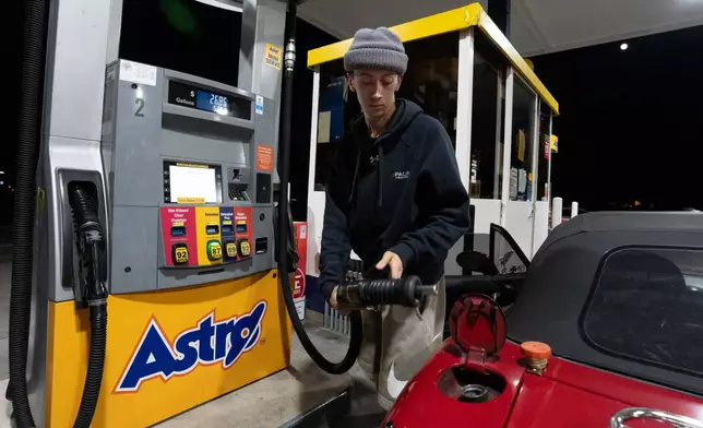 Luciano V. replaces the fuel nozzel after filling the tank of their 1999 Mazda Miata at an Astro gas station on Wednesday, April 29, 2026, in Portland, Ore. (AP Photo/Jenny Kane)