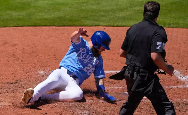 Kansas City Royals' Kyle Isbel slides home to score on a two-run single hit by Salvador Perez during the fifth inning of a baseball game against the Seattle Mariners, Sunday, May 24, 2026, in Kansas City, Mo. (AP Photo/Charlie Riedel)