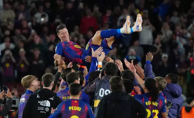 Barcelona's Robert Lewandowski is thrown into the air by his teammates after his last game for the club at the end of the Spanish La Liga soccer match between FC Barcelona and Real Betis in Barcelona, Spain, Sunday, May 17, 2026. (AP Photo/Joan Mateu Parra)