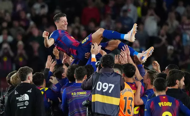 Barcelona's Robert Lewandowski is thrown into the air by his teammates after his last game for the club at the end of the Spanish La Liga soccer match between FC Barcelona and Real Betis in Barcelona, Spain, Sunday, May 17, 2026. (AP Photo/Joan Mateu Parra)