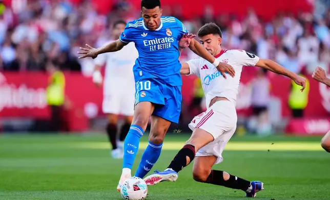 Real Madrid's Kylian Mbappe, left, duels for the ball with Sevilla's Kike Salas during the Spanish La Liga soccer match at the Ramon Sanchez Pizjuan stadium in Seville, Spain, Sunday, May 17, 2026. (AP Photo/Jose Breton)