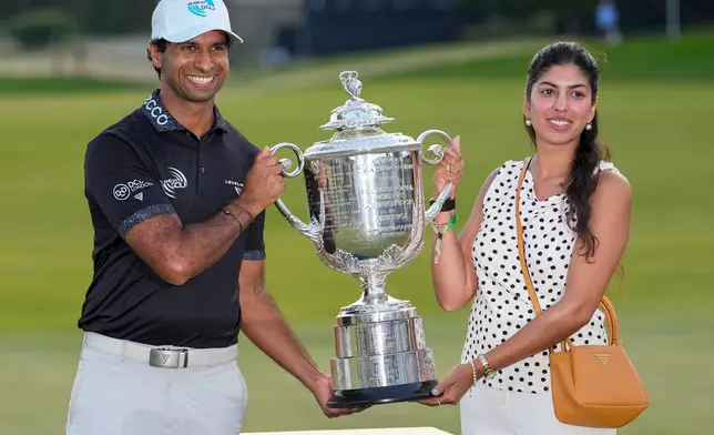 Aaron Rai, of England, and wife Gaurika Bishnoi hold the Wanamaker Trophy after winning the PGA Championship golf tournament at Aronimink Golf Club, Sunday, May 17, 2026, in Newtown Square, PA. (AP Photo/Frank Franklin II)