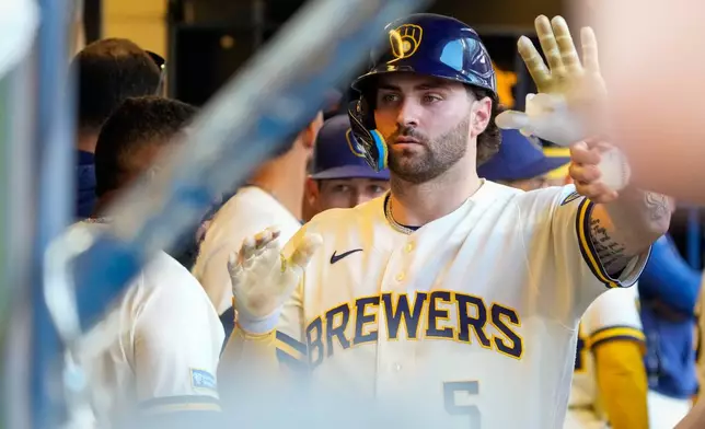 Milwaukee Brewers' Garrett Mitchell high-fives teammates after scoring on an RBI single hit by Christian Yelich during the eighth inning of a baseball game against the St. Louis Cardinals Wednesday, May 27, 2026, in Milwaukee. (AP Photo/Kayla Wolf)