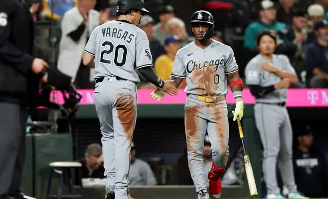 Chicago White Sox' Miguel Vargas (20) celebrates after scoring with Luisangel Acuña (0) in the ninth inning of a baseball game against the Seattle Mariners, Tuesday, May 19, 2026, in Seattle. (AP Photo/Kevin Ng)