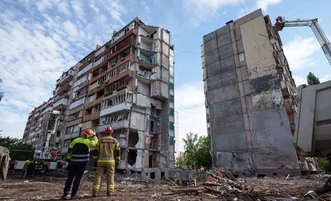 Rescue workers stand in the yard of an apartment building heavily damaged after a Russian strike on residential neighbourhood in Kyiv, Ukraine, on Friday, May 15, 2026. (AP Photo/Evgeniy Maloletka)