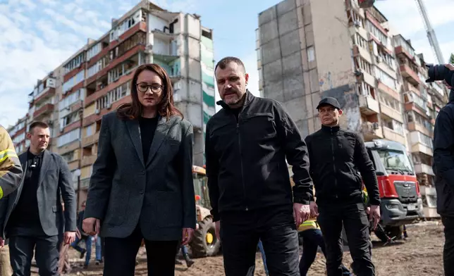 Ukraine's Prime Minister Yuliia Svyrydenko, left, and Ukraine's Interior Minister Ihor Klymenko, right, walk in the yard of an apartment building heavily damaged after a Russian strike on residential neighbourhood in Kyiv, Ukraine, on Friday, May 15, 2026. (AP Photo/Evgeniy Maloletka)