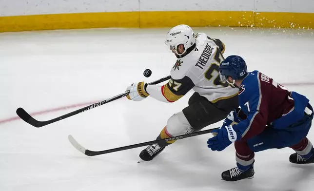 Vegas Golden Knights defenseman Shea Theodore, left, collects the puck as Colorado Avalanche defenseman Devon Toews, right, covers during the third period in Game 2 of the Western Conference finals NHL hockey Stanley Cup playoff series Friday, May 22, 2026, in Denver. (AP Photo/David Zalubowski)