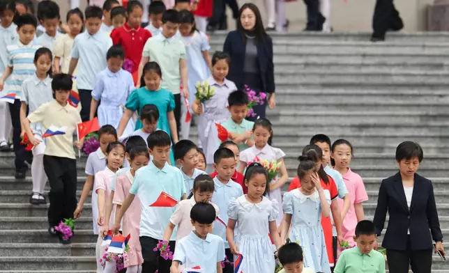 Children holding Russian and Chinese flags walk ahead of a welcoming ceremony for Russian President Vladimir Putin at the Great Hall of the People in Beijing, China Wednesday, May 20, 2026. (Maxim Shemetov/Pool Photo via AP)