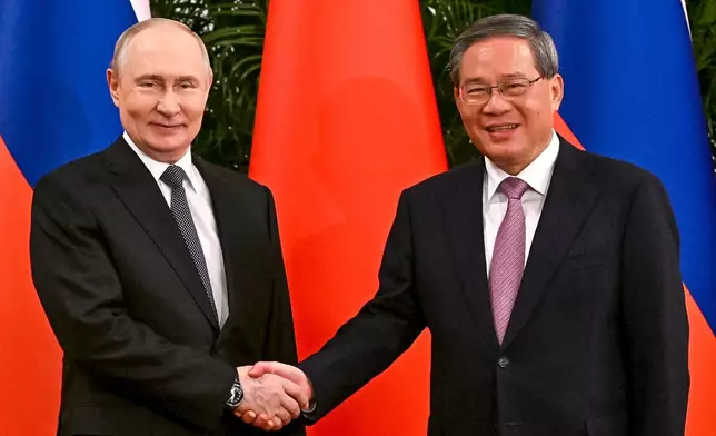 Russian President Vladimir Putin, left, and Chinese Premier Li Qiang shake hands during their meeting at the Great Hall of the People in Beijing, Wednesday, May 20, 2026. (Kristina Solovyova, Sputnik, Kremlin Pool Photo via AP)
