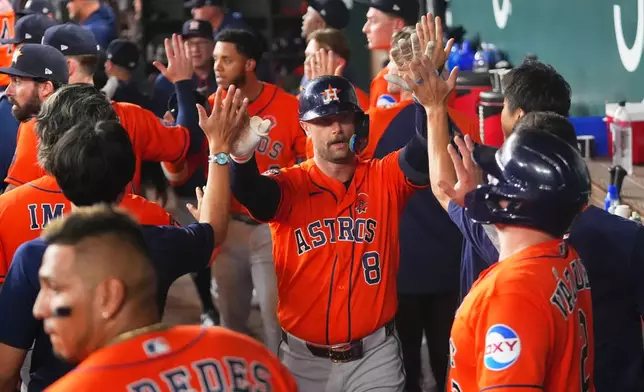 Houston Astros' Christian Walker (8) is greeted in the dugout after hitting a home run against the Texas Rangers during the seventh inning of a baseball game Monday, May 25, 2026, in Arlington, Texas. (AP Photo/Julio Cortez)