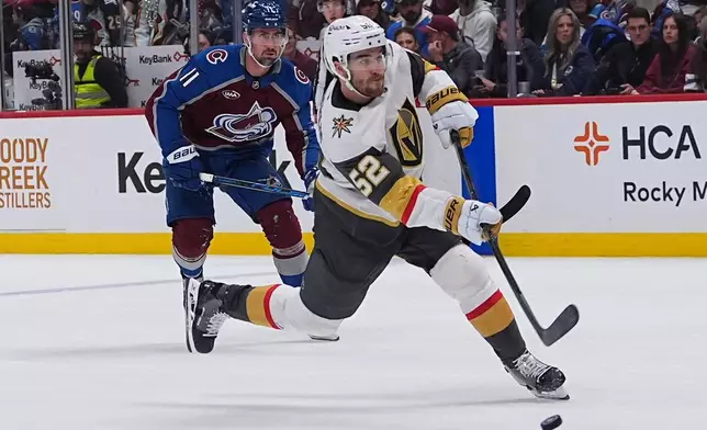 Vegas Golden Knights defenseman Dylan Coghlan, front, shoots the puck for a goal after driving past Colorado Avalanche center Brock Nelson during the second period in Game 1 of the Western Conference finals NHL hockey Stanley Cup playoff series Wednesday, May 20, 2026, in Denver. (AP Photo/David Zalubowski)