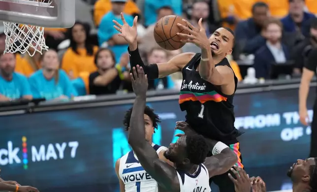San Antonio Spurs forward Victor Wembanyama (1) reaches for the ball as Minnesota Timberwolves forward Julius Randle (30) defends during the second half in Game 1 of a second-round NBA playoffs basketball series in San Antonio, Monday, May 4, 2026. (AP Photo/Eric Gay)