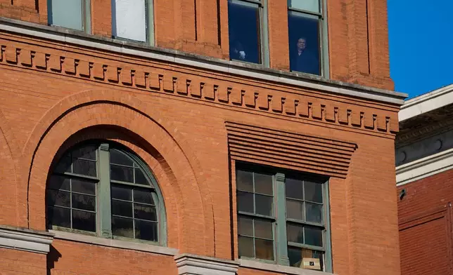 FILE - People stand at windows one floor above the 6th floor of the book depository at Dealey Plaza, on the 60th anniversary of former President John F. Kennedy's assassination, Nov. 22, 2023, in Dallas. (AP Photo/Julio Cortez, File)