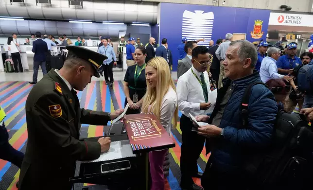 A National Guard officer checks passengers ID's prior to check in for a U.S.-bound commercial flight at Simon Bolivar International Airport in Maiquetia, Venezuela, Thursday, April 30, 2026, as direct air service between the United States and Venezuela resumes after seven years. (AP Photo/Ariana Cubillos)