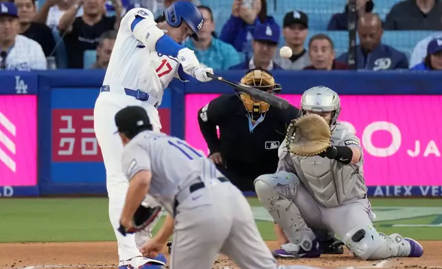 Los Angeles Dodgers' Shohei Ohtani, left, hits a solo home run as Colorado Rockies pitcher Tomoyuki Sugano, center, and catcher Hunter Goodman watch during the first inning of a baseball game Wednesday, May 27, 2026, in Los Angeles. (AP Photo/Mark J. Terrill)