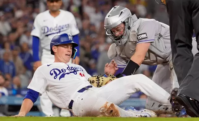 Los Angeles Dodgers' Will Smith, left, is tagged out by Colorado Rockies catcher Hunter Goodman as he tries to score on a single by Alex Call during the fourth inning of a baseball game Wednesday, May 27, 2026, in Los Angeles. (AP Photo/Mark J. Terrill)