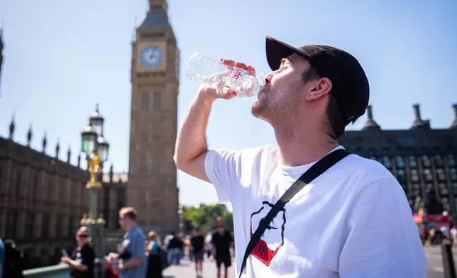 A man cools down with a bottle of water during the hot weather on Westminster Bridge, central London, England, Monday, May 25, 2026. (James Manning/PA via AP)