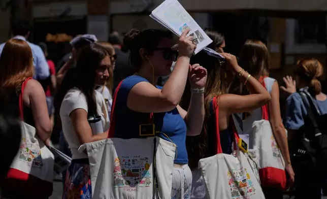 A woman shelters from the sun with a city guide in downtown Rome as temperatures are expected to reach 32 degrees Celsius (89.6 Fahrenheit), Tuesday, May 26, 2026. (AP Photo/Gregorio Borgia)