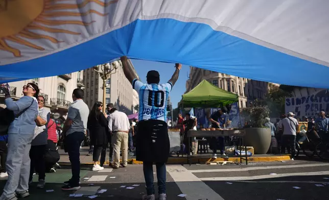 A laborer holds an Argentine flag during a May Day demonstration in Buenos Aires, Argentina, Thursday, April 30, 2026. (AP Photo/Rodrigo Abd)