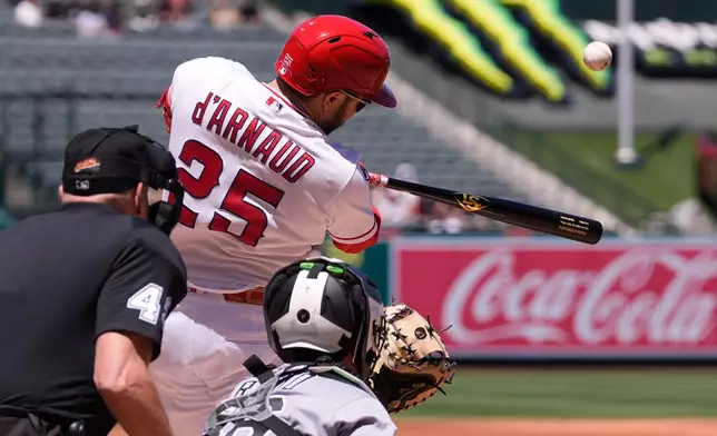 Los Angeles Angels' Travis D'Arnaud, center, hits a three-run home run as Chicago White Sox catcher Drew Romo, right, and home plate umpire Andy Fletcher watch during the second inning of a baseball game Wednesday, May 6, 2026, in Anaheim, Calif. (AP Photo/Mark J. Terrill)