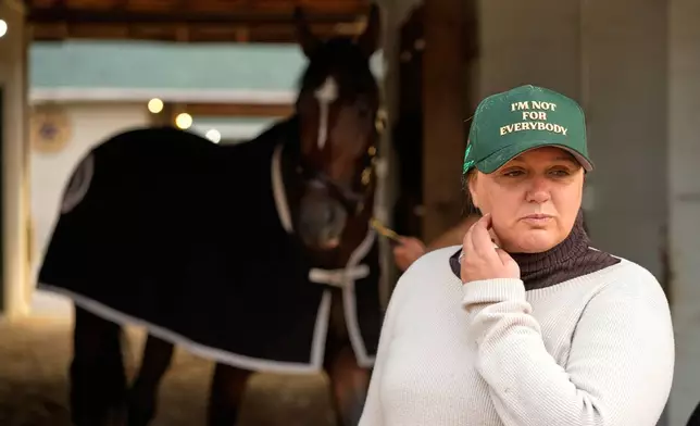 Trainer Cherie DeVaux stands watches from a barn after a workout at Churchill Downs Monday, April 27, 2026, in Louisville, Ky. (AP Photo/Charlie Riedel)