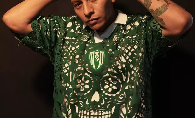 Designer Hugo Rosas poses for a photo wearing a soccer jersey, inspired by papel picado and traditional folk art, from his brand Mexclart, which he produces in his workshop in Cuautitlán Izcalli, Mexico, Monday, May 25, 2026. (AP Photo/Marco Ugarte)