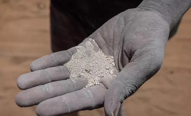 A worker shows the chemical fertilizer that is used across the country in Thies, Senegal, Tuesday, May 12, 2026. (AP Photo/Caitlin Kelly)