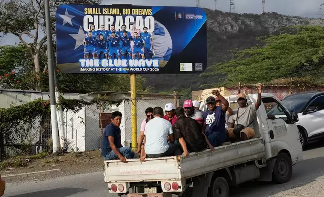 Commuters drive past a billboard displaying the Curacao national soccer team in Willemstad, Curacao, Friday, May 15, 2026. (AP Photo/Matias Delacroix)