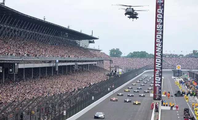 Helicopters fly over the field on the parade lap before the Indianapolis 500 auto race at Indianapolis Motor Speedway in Indianapolis, Sunday, May 24, 2026. (AP Photo/Michael Conroy)