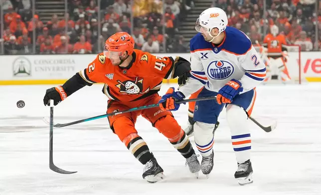 Anaheim Ducks center Tim Washe, left, and Edmonton Oilers defenseman Evan Bouchard battle for the puck during the third period of Game 6 in the first round of the NHL hockey Stanley Cup playoffs series Thursday, April 30, 2026, in Anaheim, Calif. (AP Photo/Mark J. Terrill)
