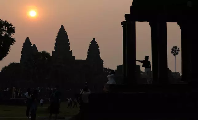 Visitors pose for photos as the sun rises over the ancient temple of Angkor Wat in Siem Reap, Cambodia on April 9, 2023. (AP Photo/Anton L. Delgado)