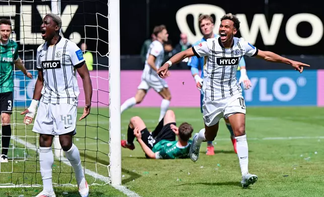 Elversberg's Bambase Conte, right, celebrates scoring their first goal of the game during the Bundesliga 2 soccer match between SV Elversberg and SC Preußen Münster in Spiesen-Elversberg, Germany, Sunday May 17, 2026. (Uwe Anspach/dpa via AP)
