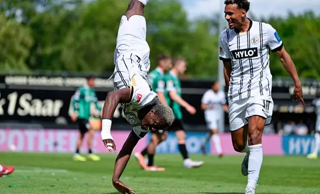 Elversberg's David Mokwa, left, celebrates scoring their second goal of the game with Bambase Conte during the Bundesliga 2 soccer match between SV Elversberg and SC Preußen Münster in Spiesen-Elversberg, Germany, Sunday May 17, 2026. (Uwe Anspach/dpa via AP)