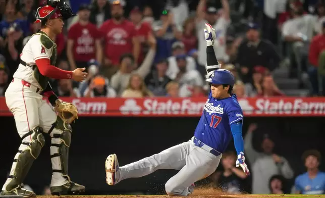 Los Angeles Dodgers' Shohei Ohtani, right, scores on his two-run triple after a throwing error as Los Angeles Angels catcher Logan O'Hoppe stands at the plate during the eighth inning of a baseball game Saturday, May 16, 2026, in Anaheim, Calif. (AP Photo/Mark J. Terrill) CORRECTION: After official review, changed from three-run inside-the-park home run to two-run triple after a throwing error