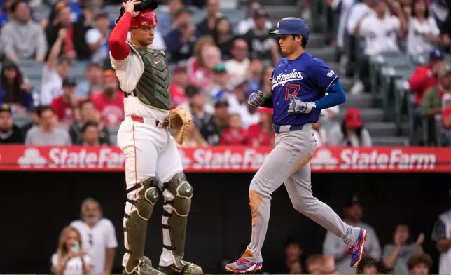 Los Angeles Dodgers' Shohei Ohtani, right, scores on a sacrifice fly by Will Smith as Los Angeles Angels catcher Logan O'Hoppe stands at the plate during the first inning of a baseball game Saturday, May 16, 2026, in Anaheim, Calif. (AP Photo/Mark J. Terrill)
