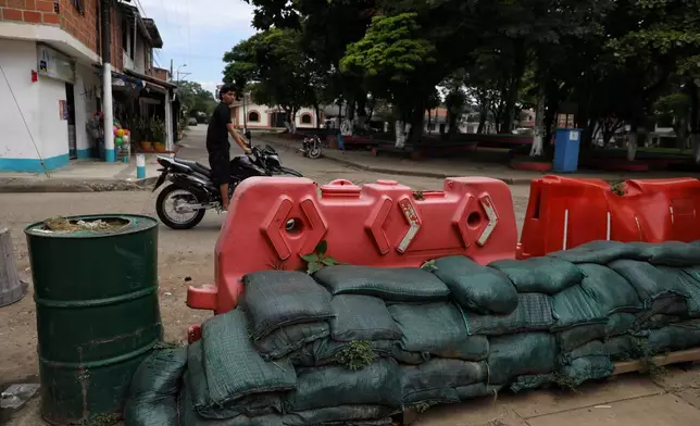 A man rides his motorcycle past a barricade blocking streets in Potrerito, Colombia, Tuesday, May 19, 2026, following attacks by dissidents of the former Revolutionary Armed Forces of Colombia, or FARC. (AP Photo/Santiago Saldarriaga)