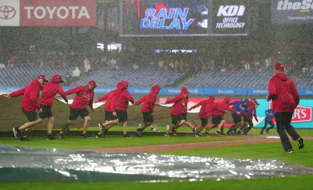 Grounds crew members pull a tarp onto the field during the sixth inning of the second baseball game of a doubleheader between the Philadelphia Phillies and the San Francisco Giants, Thursday, April 30, 2026, in Philadelphia. (AP Photo/Derik Hamilton)