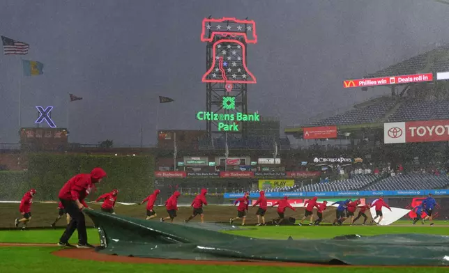 Grounds crew members pull a tarp onto the field during the sixth inning of the second baseball game of a doubleheader between the Philadelphia Phillies and the San Francisco Giants, Thursday, April 30, 2026, in Philadelphia. (AP Photo/Derik Hamilton)