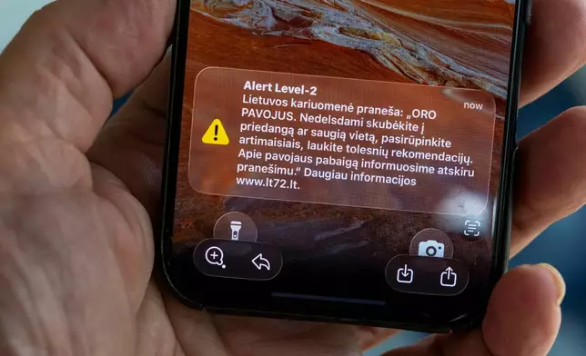 The phone shows the received message "The Lithuanian military reports: "AIR DANGER. Hurry to cover or a safe place without delay, take care of your loved ones, wait for further recommendations. We will inform you about the end of the danger in a separate message", in Vilnius, Lithuania, Wednesday, May 20, 2026. (AP Photo/Mindaugas Kulbis)