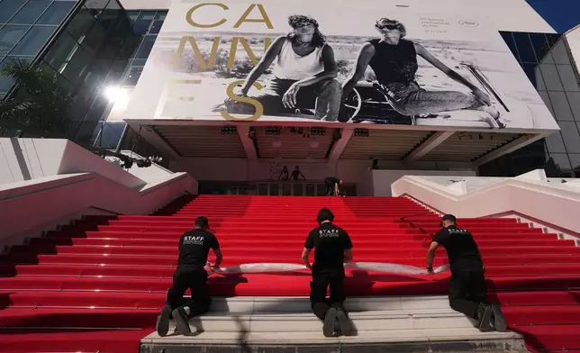 Crew members install the red carpet at the Palais des Festivals ahead of the opening ceremony of the 79th international film festival, Cannes, southern France, Tuesday, May 12, 2026. (AP Photo/Andreea Alexandru)