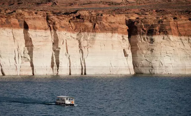 FILE - A boat floats past bathtub rings showing how low Lake Powell levels have dropped June 7, 2022, in Page, Ariz. (AP Photo/Brittany Peterson, File)