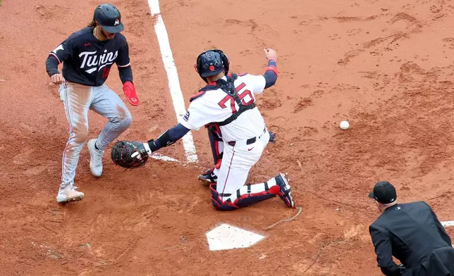 Minnesota Twins' Austin Martin, left, scores as Boston Red Sox catcher Carlos Narváez (75) misses a catch during the sixth inning of a baseball game, Sunday, May 24, 2026, in Boston. (AP Photo/Mark Stockwell)