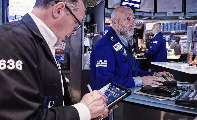 Trader Edward Curran, left, and specialist Meric Greenbaum, center, work on the floor of the New York Stock Exchange, Friday, May 22, 2026. (AP Photo/Richard Drew)