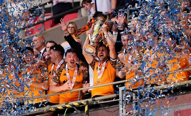 Hull City's Lewis Coyle lifts the trophy after winning promotion to the Premier League following the Championship play-off final between Hull City and Middlesbrough at Wembley Stadium, London, Saturday May 23, 2026. (Jordan Pettitt/PA via AP)