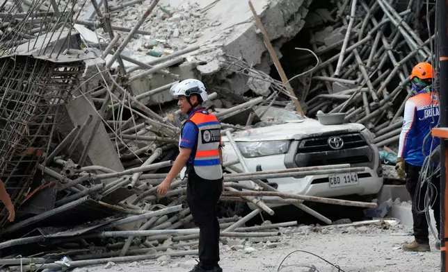 Rescuers stand beside ruins as search operations continue at a collapsed building in Angeles city in Pampanga province, north of Manila, Monday, May 25, 2026. (AP Photo/Aaron Favila)