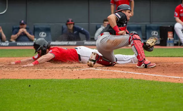 Cleveland Guardians' Austin Hedges is safe at home plate on a sacrifice fly by Jose Ramirez as Washington Nationals' Drew Millas waits for the throw during the fifth inning a baseball game, Wednesday, May 27, 2026, in Cleveland. (AP Photo/Phil Long)